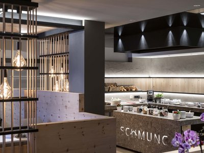 Hotel Schmung – Ihr Hotel auf der Seiser Alm Modernes Frühstücksbuffet mit Holzakzenten und warmen Lichtern