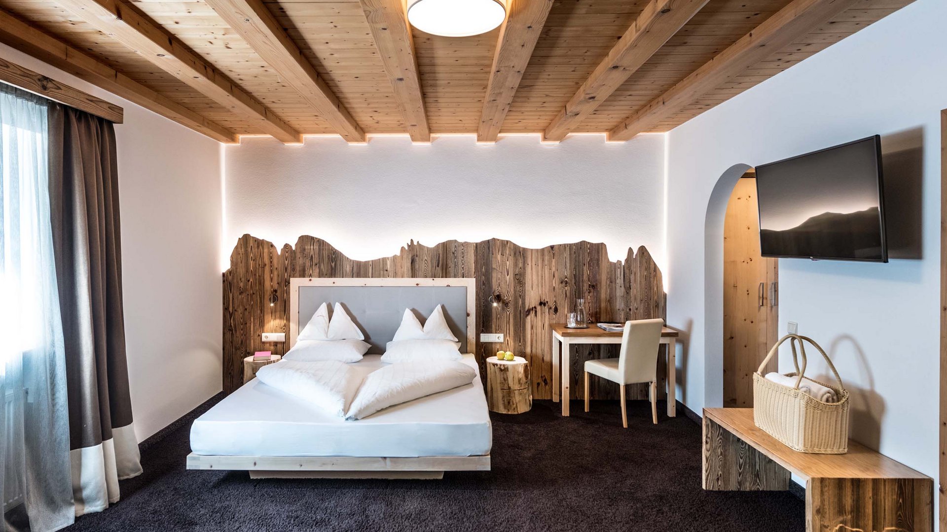 Hotel Schmung – Ihr Hotel auf der Seiser Alm Gemütliches Schlafzimmer mit Holzdecke und Bergmotiv-Holzdekoration