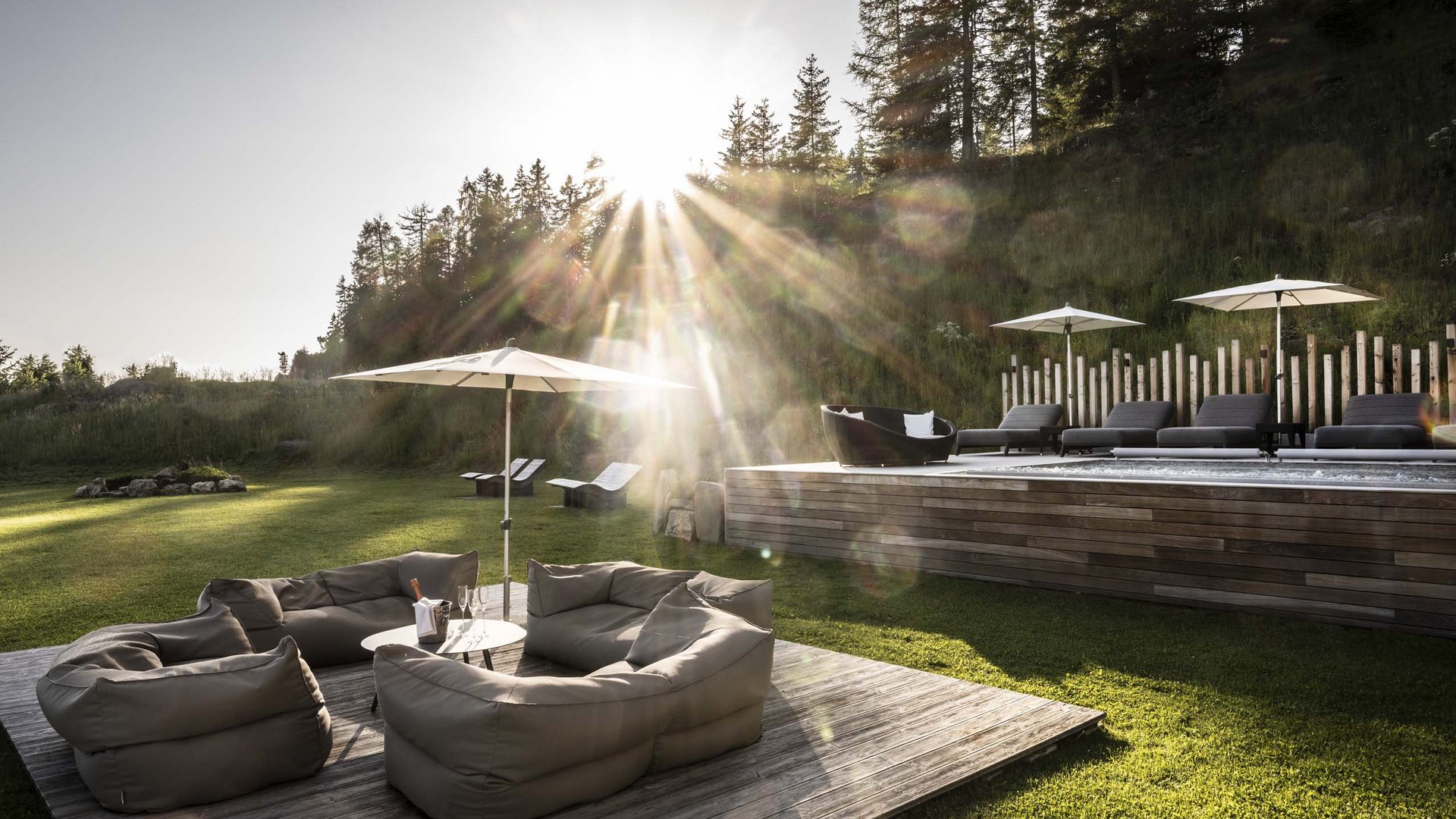 Hotel Schmung – Ihr Hotel auf der Seiser Alm Sonnenuntergang über moderner Lounge mit Sitzsäcken und Pool im Garten