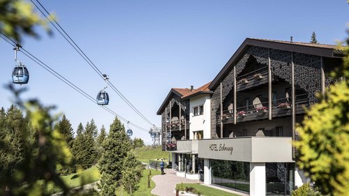 Hotel Schmung – Ihr Hotel auf der Seiser Alm Hotel Schmung mit Seilbahnkabinen in grüner Berglandschaft unter blauem Himmel