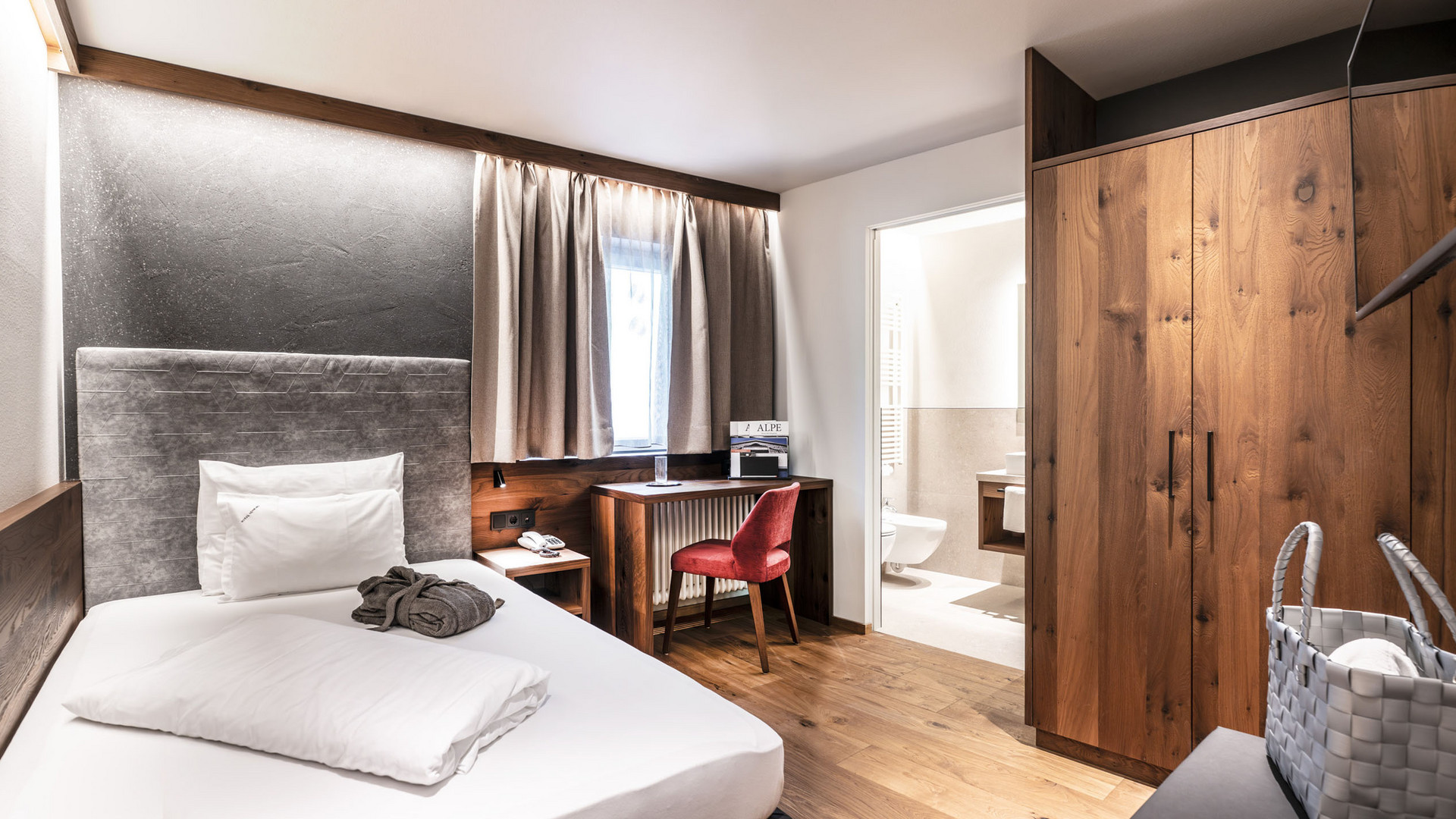 Hotel Schmung – Ihr Hotel auf der Seiser Alm Modernes Einzelzimmer mit Holzmöbeln und Blick ins Badezimmer