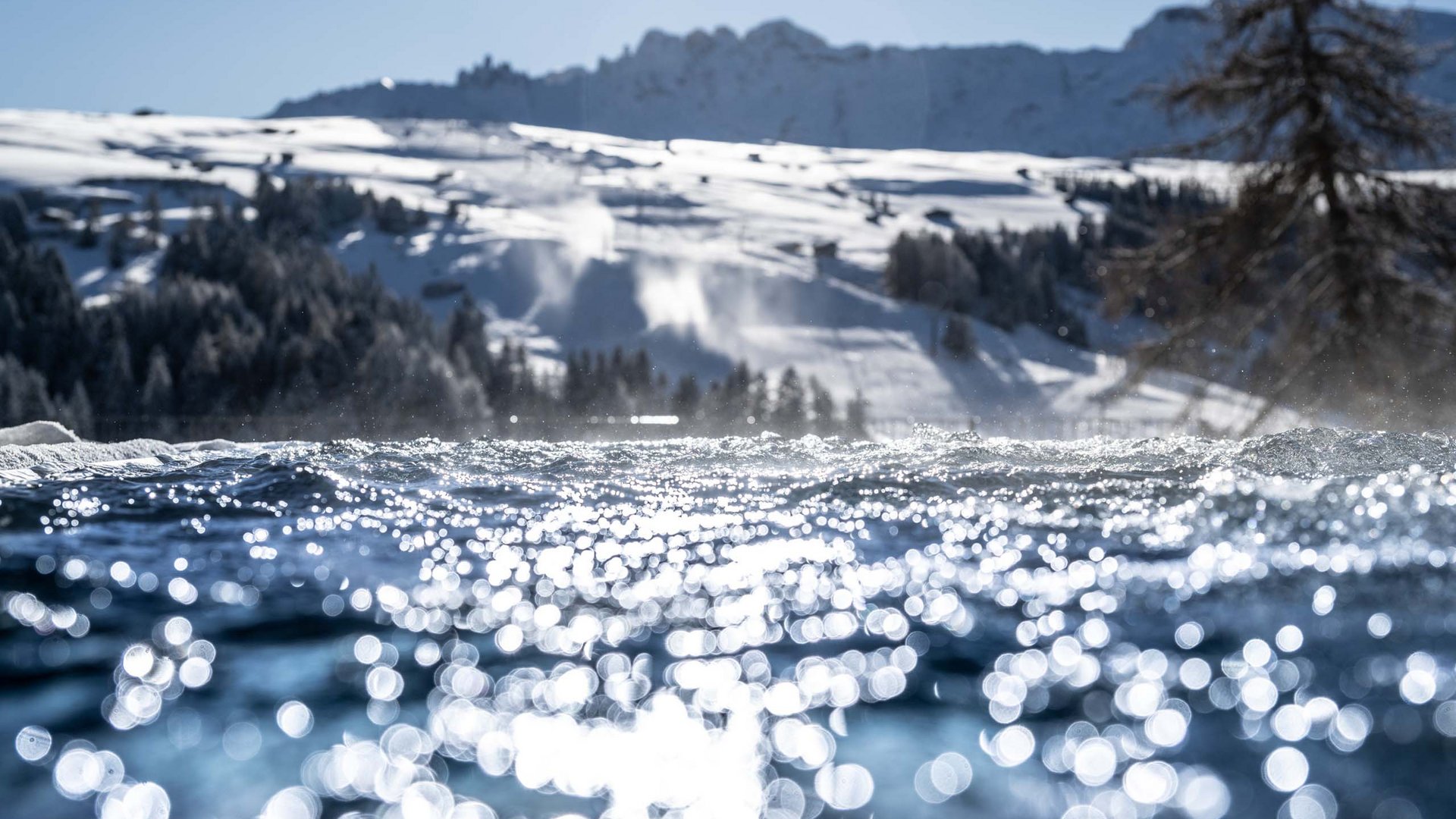 Hotel Schmung – Ihr Hotel auf der Seiser Alm Glitzerndes Wasser vor schneebedeckten Bergen im Sonnenlicht