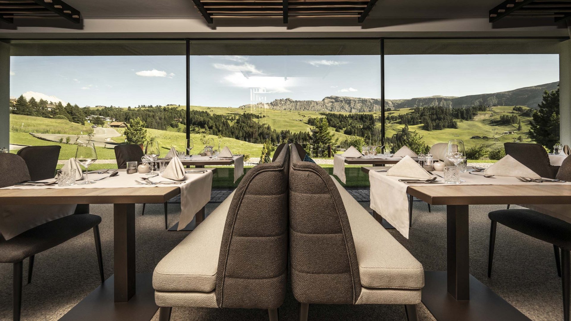 Hotel Schmung – Ihr Hotel auf der Seiser Alm Restaurant mit Blick auf grüne Hügel und Berge durch große Fenster